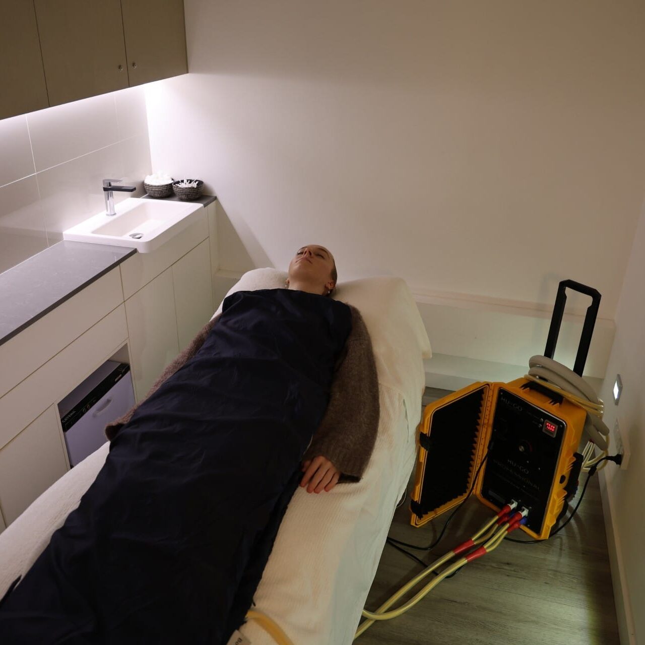 Client receiving HUGO High Intensity PEMF therapy on dual mats